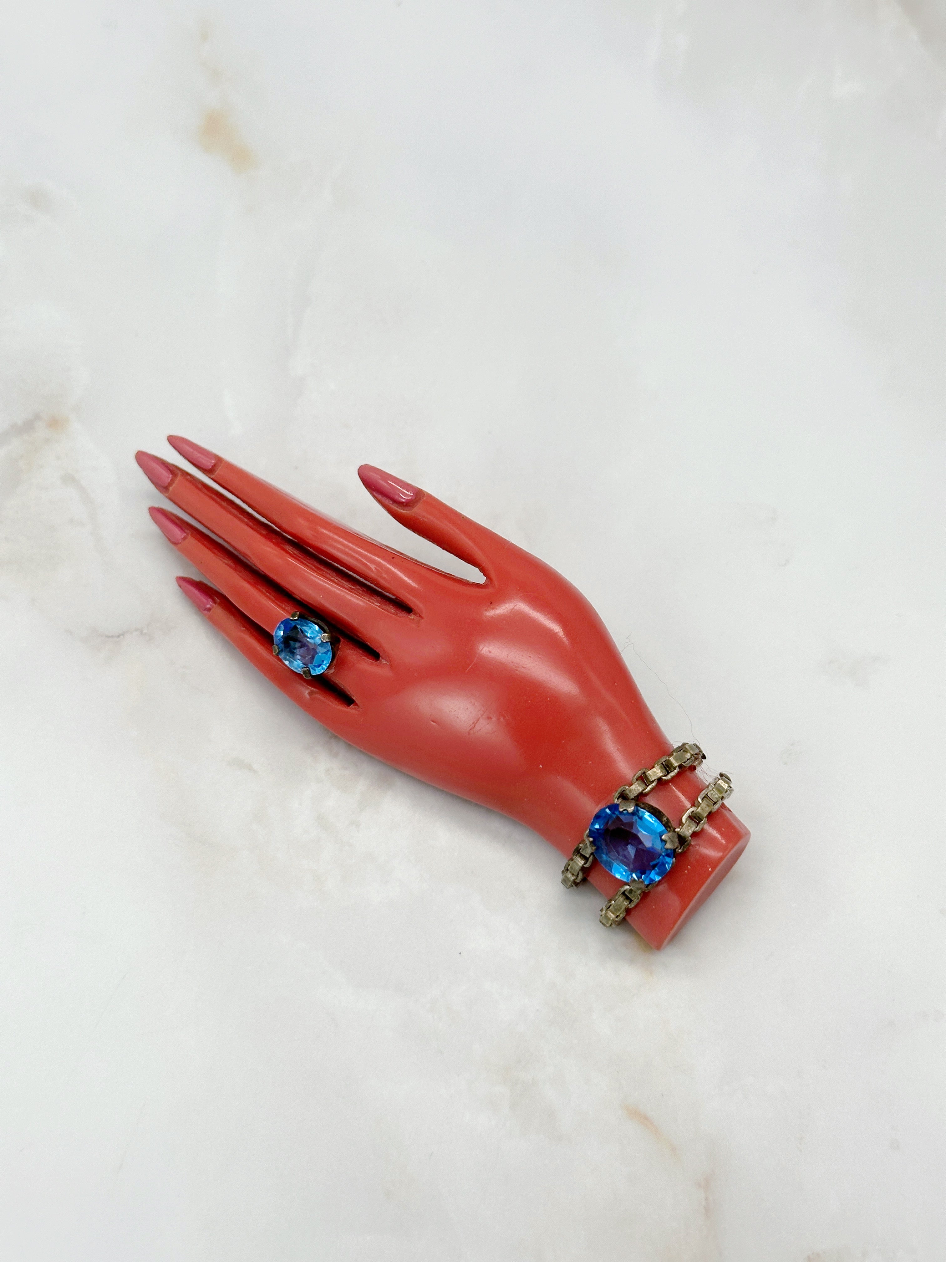 Ausgefallene Brosche mit korallfarbener Bakelit-Hand und blauen Glaskristallen